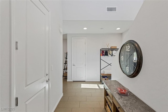 corridor featuring light tile patterned floors, baseboards, visible vents, and recessed lighting