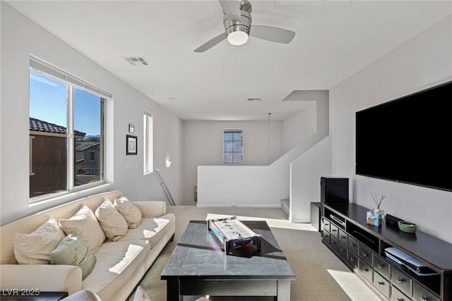 living room featuring light carpet, visible vents, and a ceiling fan