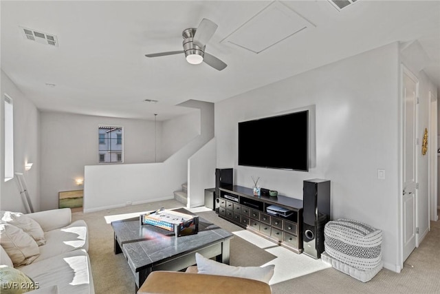 living area featuring stairway, carpet, visible vents, and ceiling fan