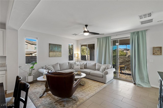 living room featuring visible vents, a ceiling fan, and baseboards