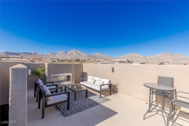 view of patio / terrace with a mountain view, an outdoor living space with a fireplace, and fence