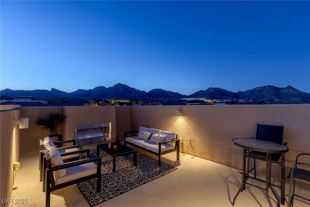 view of patio with a lit fireplace and a mountain view