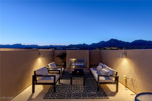 view of patio / terrace with an outdoor living space with a fireplace and a mountain view