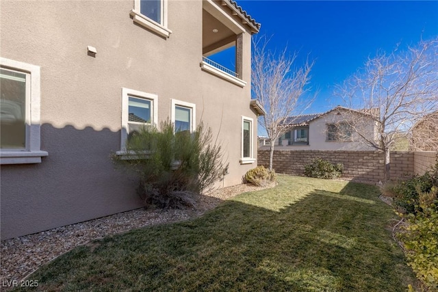 view of property exterior with fence, a lawn, and stucco siding