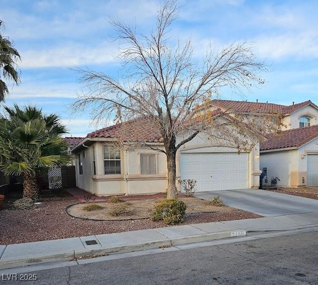 view of front facade featuring a garage, concrete driveway, a tile roof, and stucco siding