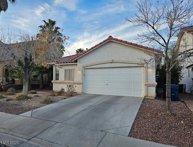 mediterranean / spanish home featuring an attached garage, driveway, a tiled roof, and stucco siding