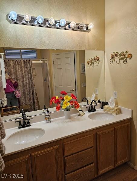 full bath with wood finished floors, a shower, double vanity, and a sink