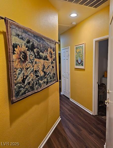 hallway featuring dark wood-style flooring, visible vents, and baseboards