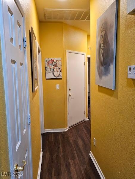 hall with wood finished floors, visible vents, and baseboards