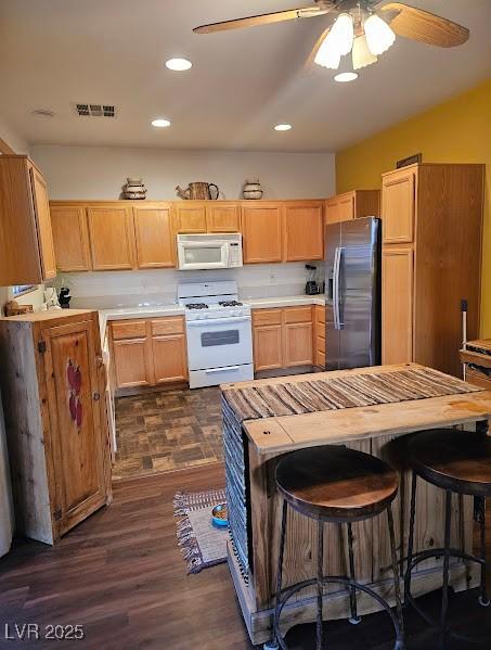 kitchen featuring white appliances, visible vents, dark wood finished floors, a ceiling fan, and light countertops