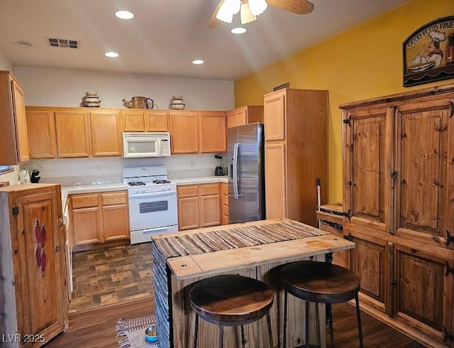 kitchen featuring white appliances, visible vents, light countertops, and dark wood-style flooring