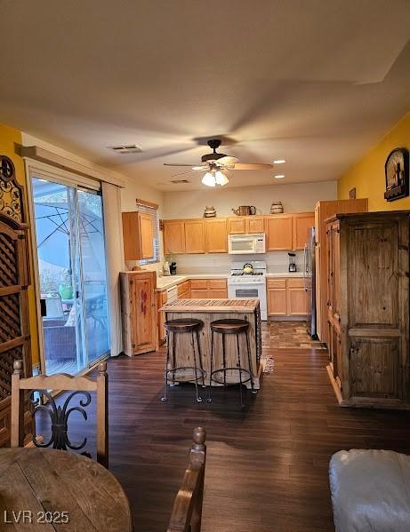 kitchen featuring light brown cabinets, white appliances, dark wood-type flooring, visible vents, and light countertops