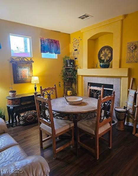 dining room featuring wood finished floors, a tile fireplace, and visible vents