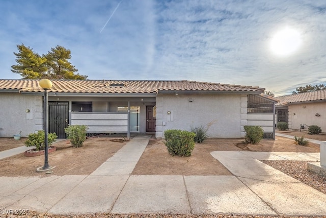 view of front facade with a tile roof, a gate, and stucco siding