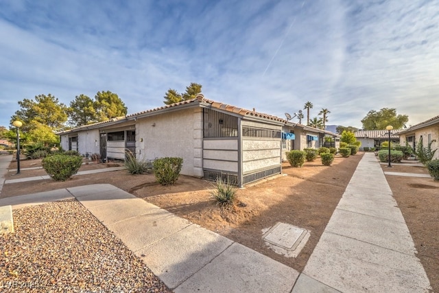 exterior space with a tiled roof and stucco siding