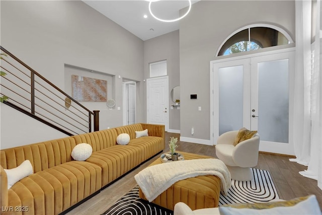 living room featuring french doors, a high ceiling, wood finished floors, baseboards, and stairs