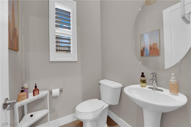 bathroom with baseboards, a sink, and toilet