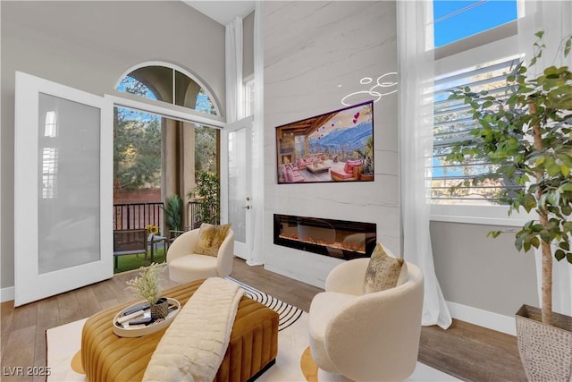 living area with wood finished floors, a glass covered fireplace, and baseboards