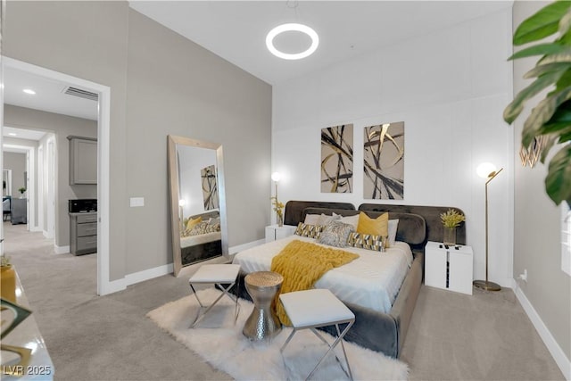 bedroom with light carpet, a high ceiling, visible vents, and baseboards