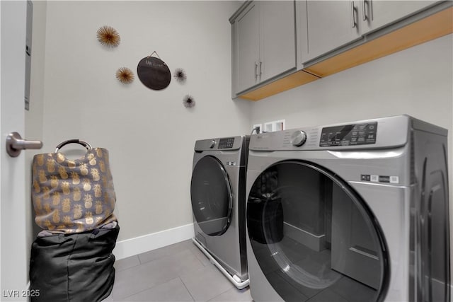 laundry area with baseboards, cabinet space, washing machine and clothes dryer, and light tile patterned floors