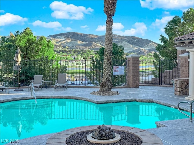 community pool with a fire pit, a patio area, fence, and a mountain view