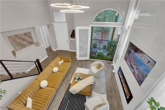 living room featuring stairs, a high ceiling, baseboards, and wood finished floors