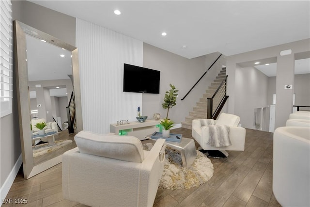 living room featuring light wood-style floors, recessed lighting, and stairway