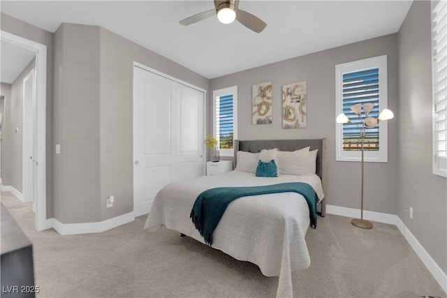 bedroom featuring light carpet, multiple windows, a closet, and baseboards