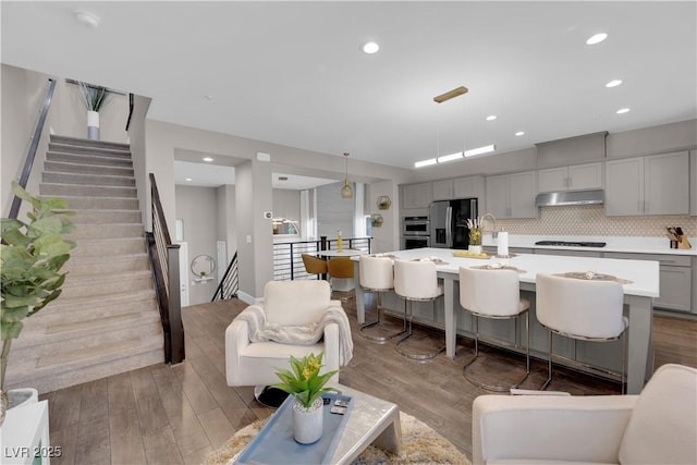 living area with light wood-style floors, recessed lighting, and stairs