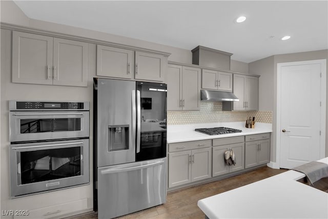 kitchen with appliances with stainless steel finishes, gray cabinets, light countertops, and under cabinet range hood