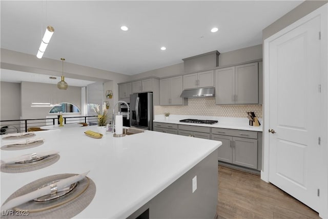 kitchen featuring appliances with stainless steel finishes, light countertops, decorative light fixtures, and under cabinet range hood