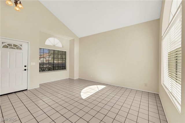 unfurnished room featuring high vaulted ceiling, light tile patterned flooring, and plenty of natural light