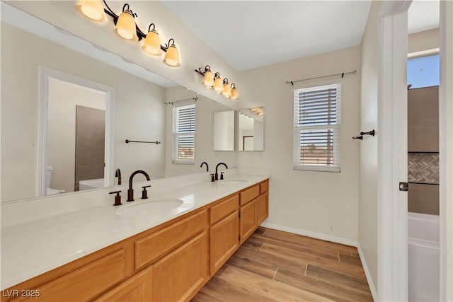 full bathroom with a healthy amount of sunlight, a sink, and wood finished floors