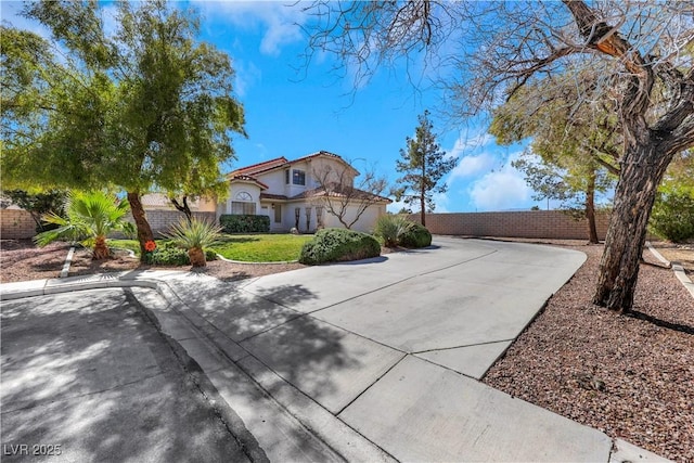 mediterranean / spanish home featuring driveway, fence, and a front lawn