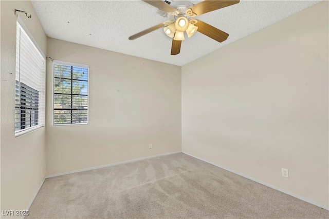 empty room with light colored carpet, ceiling fan, a textured ceiling, and baseboards