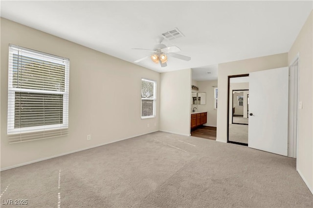 spare room featuring a ceiling fan, carpet flooring, and visible vents