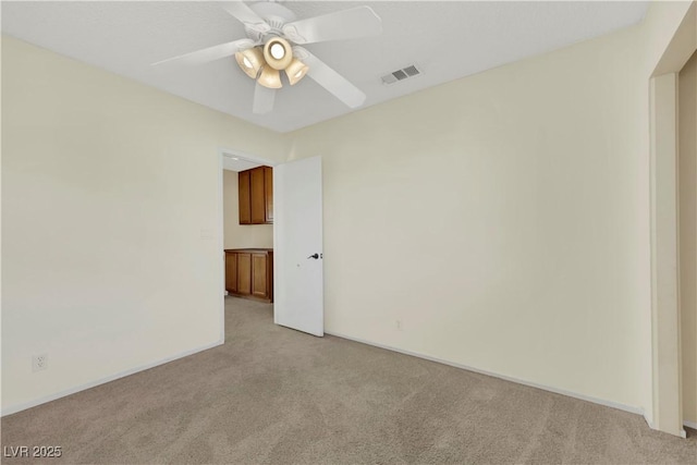 unfurnished room featuring ceiling fan, visible vents, baseboards, and light colored carpet