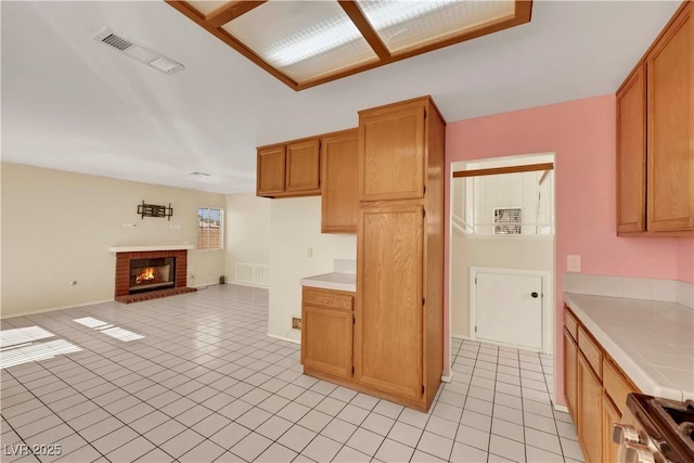 kitchen with light tile patterned flooring, stove, visible vents, open floor plan, and tile counters