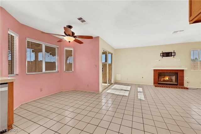 unfurnished living room featuring a ceiling fan, light tile patterned flooring, visible vents, and a brick fireplace