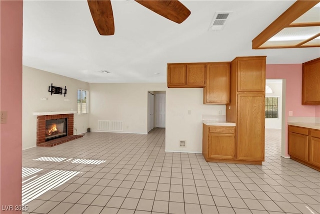 kitchen with brown cabinetry, visible vents, light countertops, and open floor plan