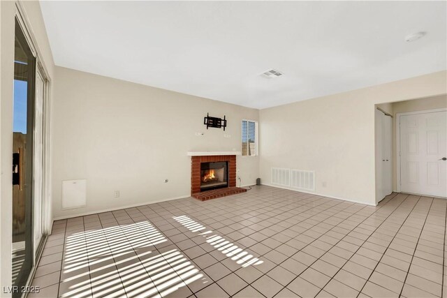 unfurnished living room with baseboards, a fireplace, visible vents, and light tile patterned flooring