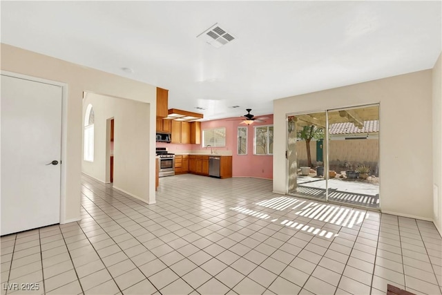 unfurnished living room featuring ceiling fan, light tile patterned flooring, visible vents, and baseboards