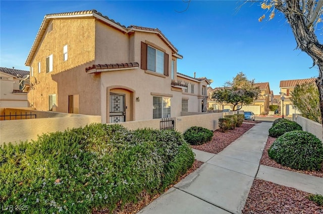 view of side of property featuring a fenced front yard, a tile roof, and stucco siding