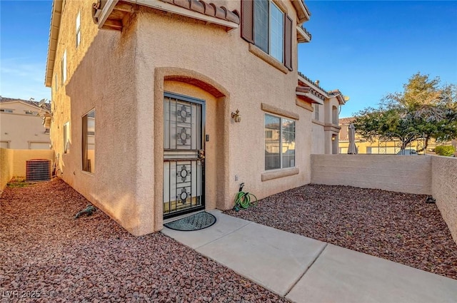 view of exterior entry featuring fence and stucco siding