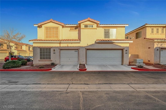 mediterranean / spanish-style house featuring an attached garage, driveway, a tiled roof, and stucco siding