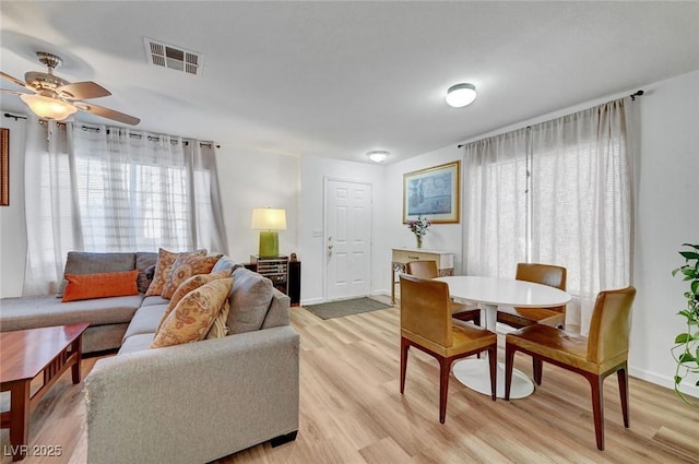 living area featuring ceiling fan, light wood-type flooring, visible vents, and baseboards