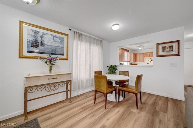 dining area featuring baseboards, track lighting, and light wood-style floors