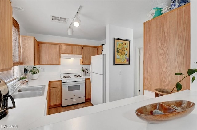 kitchen with white appliances, visible vents, light countertops, under cabinet range hood, and a sink