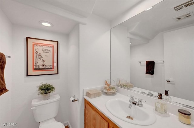 half bath featuring visible vents, vanity, and toilet