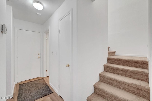 interior space featuring stairs, light wood-style flooring, and baseboards